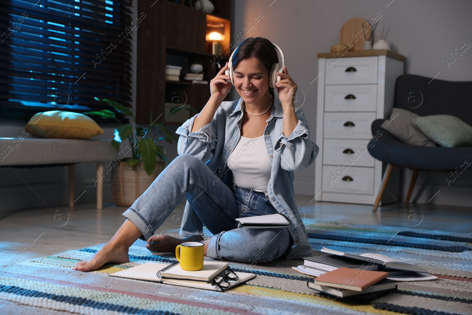 Photo of Happy student in headphones preparing for exam on floor at home