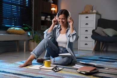 Photo of Happy student in headphones preparing for exam on floor at home