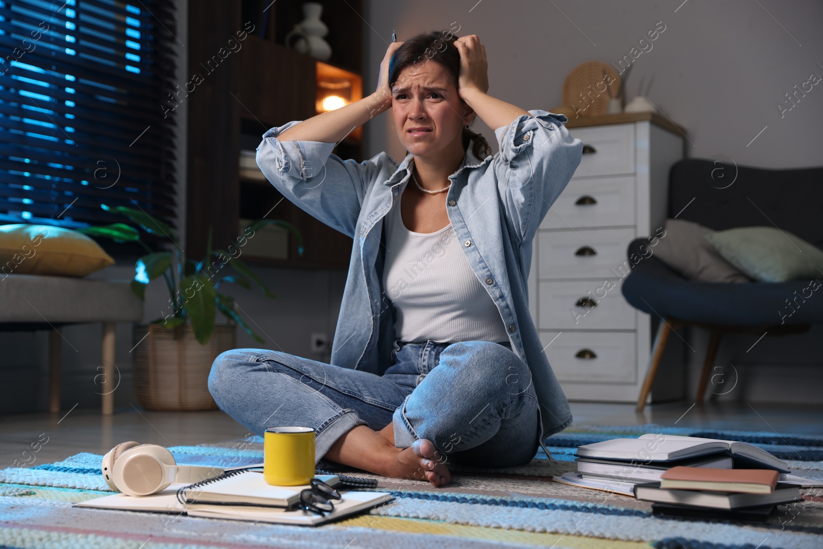 Photo of Worried student preparing for exam on floor at home