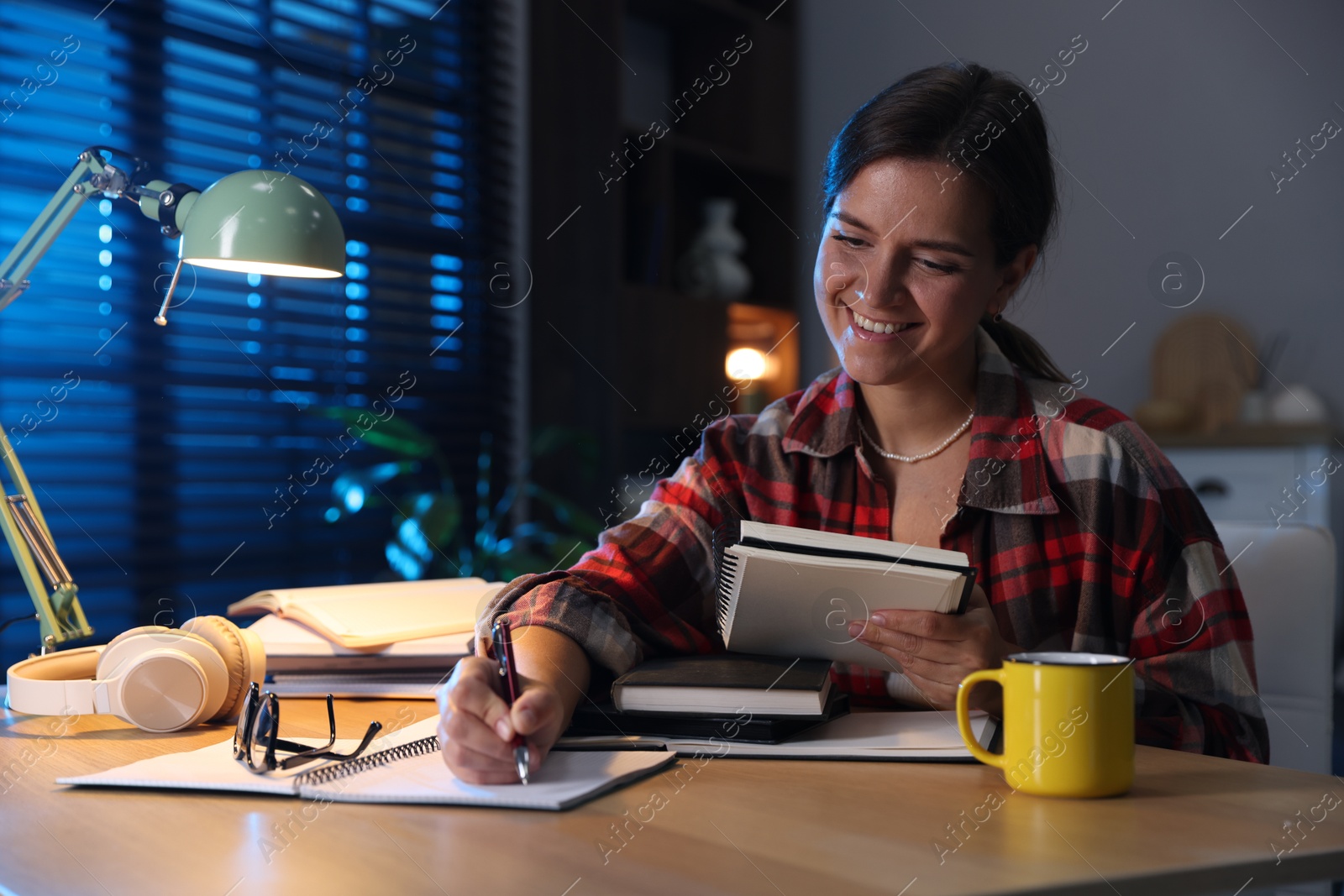 Photo of Happy student preparing for exam at wooden desk indoors