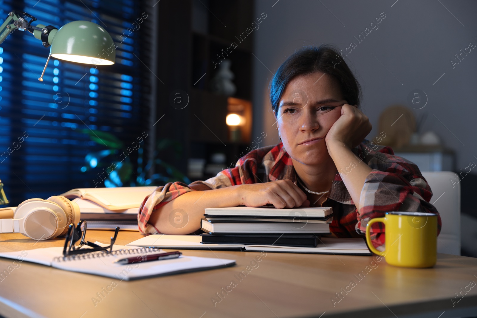 Photo of Tired student preparing for exam at wooden desk indoors