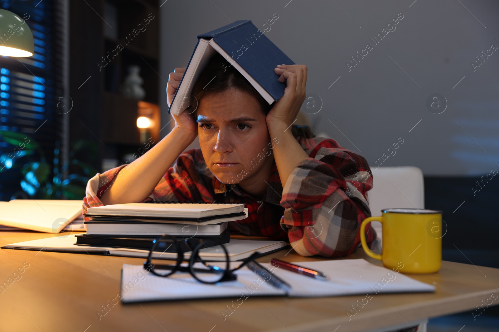 Photo of Tired student preparing for exam at wooden desk indoors