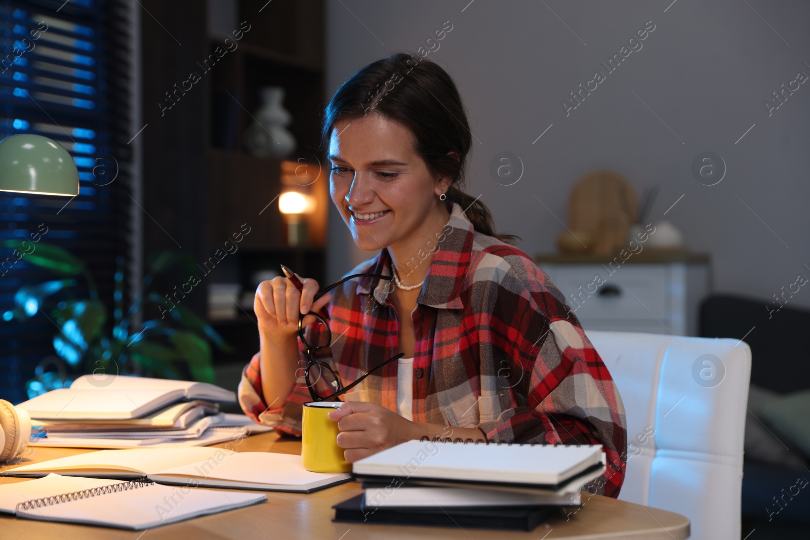 Photo of Happy student preparing for exam at wooden desk indoors