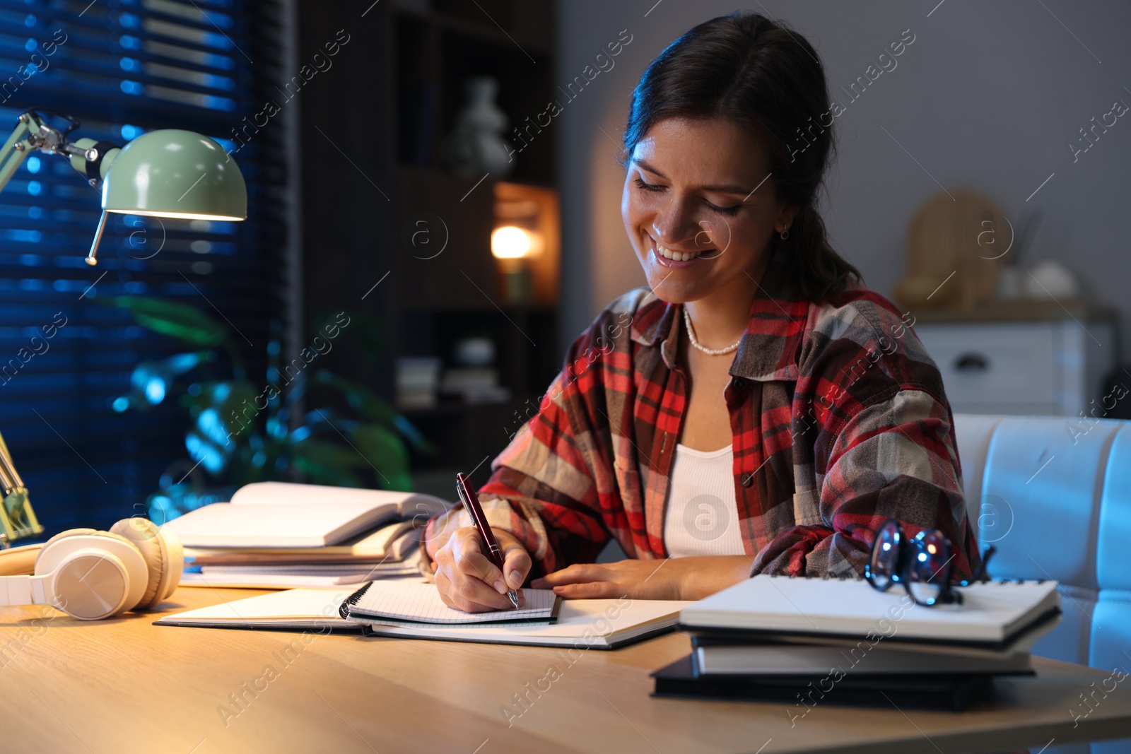 Photo of Happy student preparing for exam at wooden desk indoors