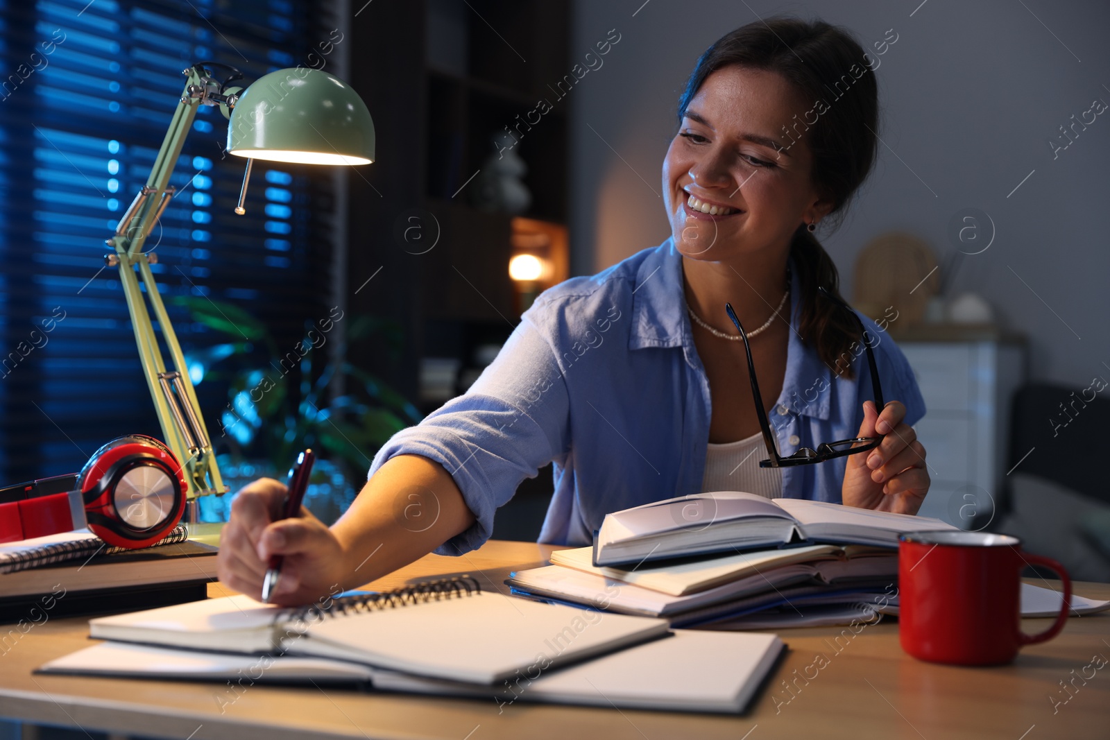 Photo of Happy student preparing for exam at wooden desk indoors