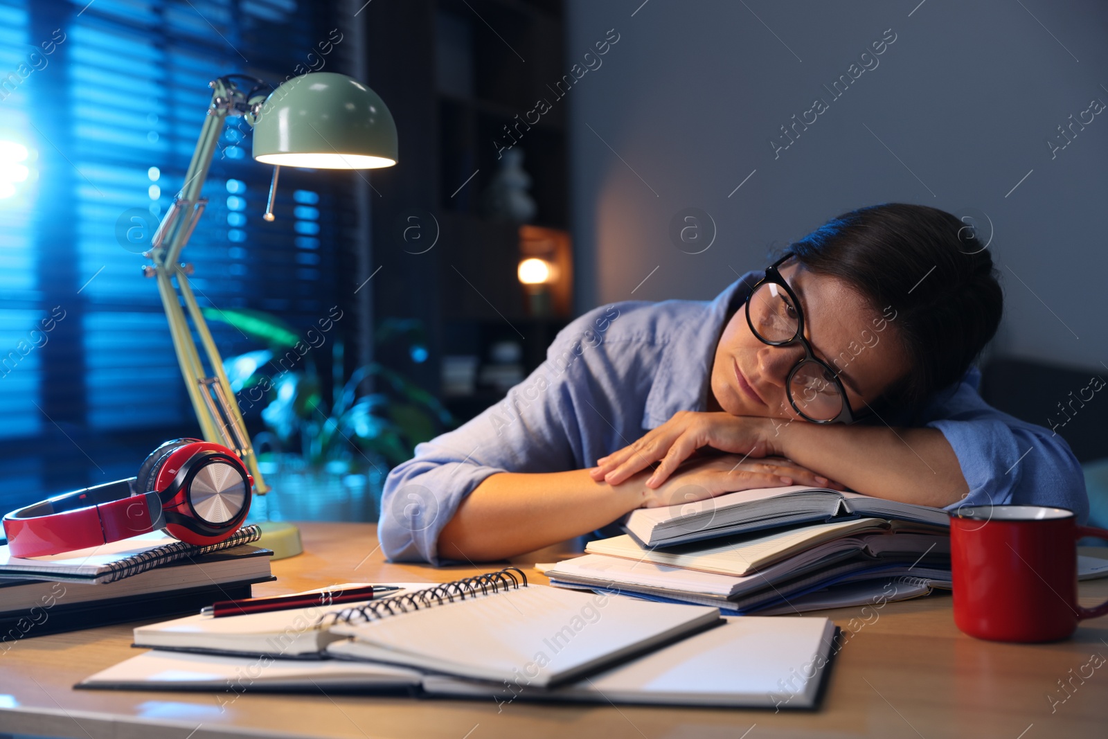 Photo of Tired student preparing for exam at wooden desk indoors