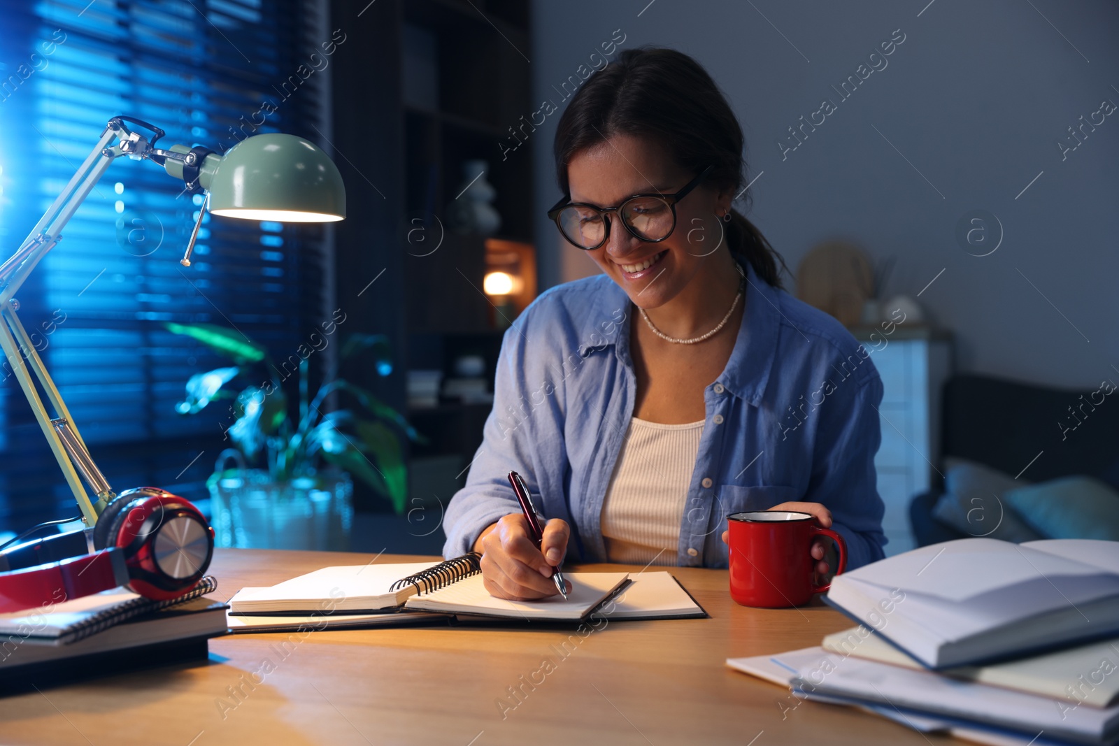 Photo of Happy student preparing for exam at wooden desk indoors