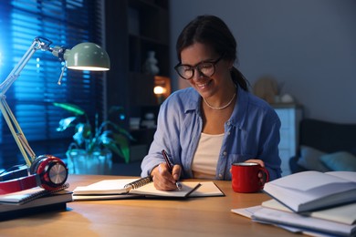 Photo of Happy student preparing for exam at wooden desk indoors