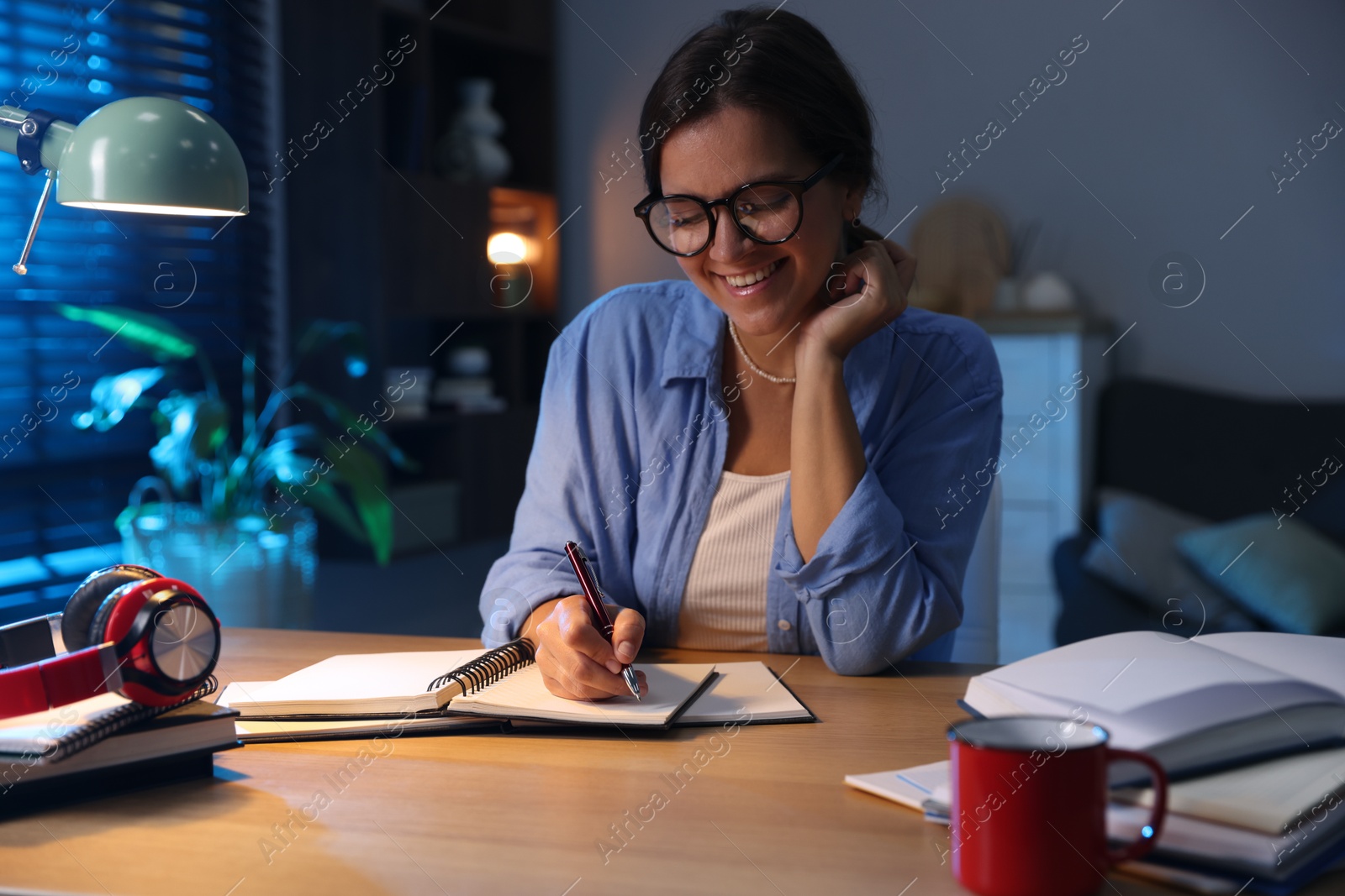 Photo of Happy student preparing for exam at wooden desk indoors