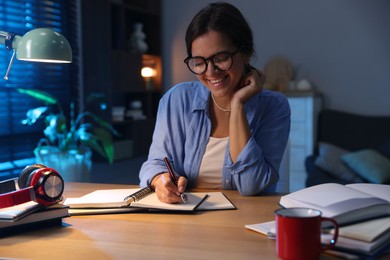 Photo of Happy student preparing for exam at wooden desk indoors
