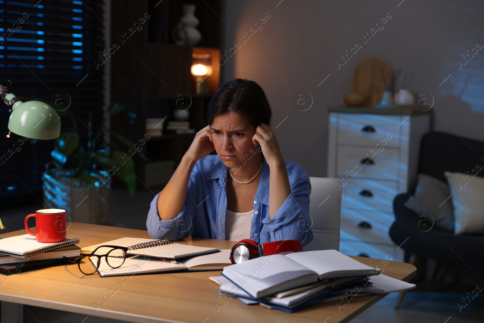Photo of Worried student preparing for exam at wooden desk indoors