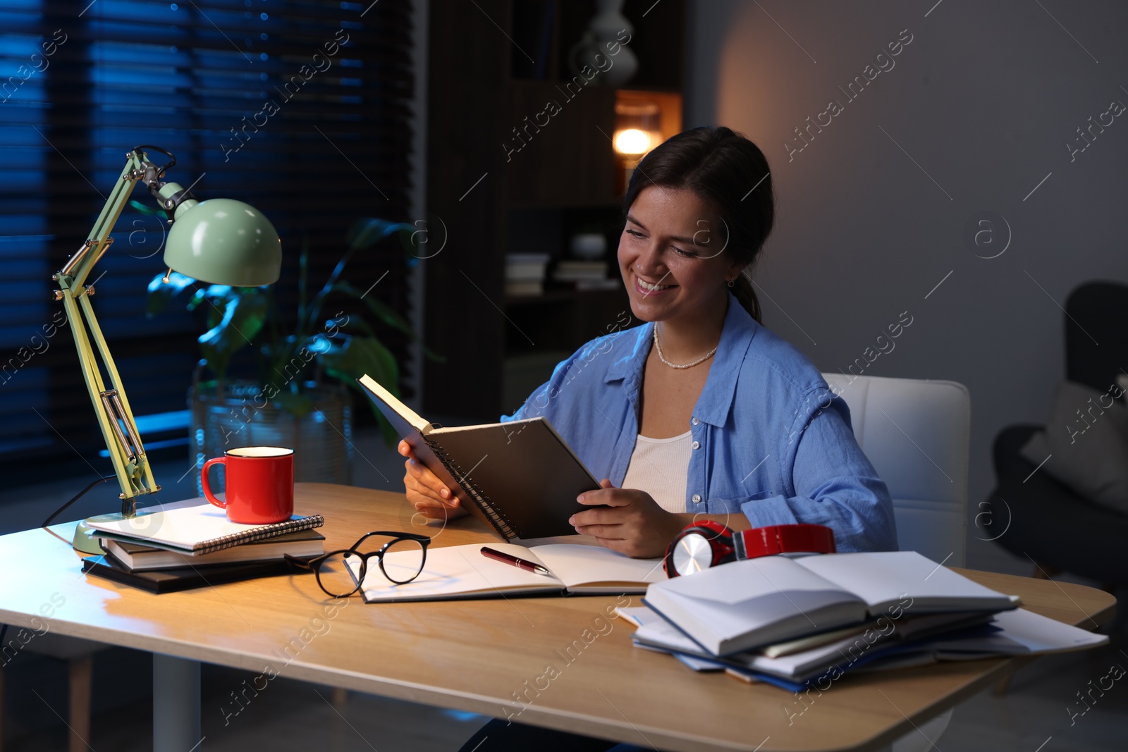 Photo of Happy student preparing for exam at wooden desk indoors