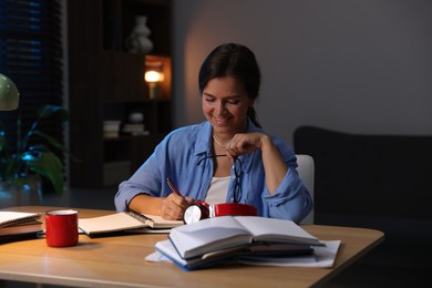 Photo of Happy student preparing for exam at wooden desk indoors