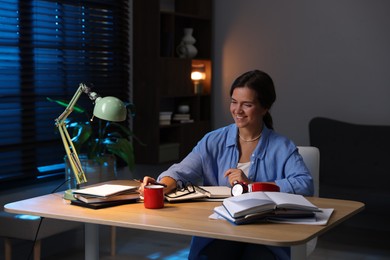 Photo of Happy student preparing for exam at wooden desk indoors