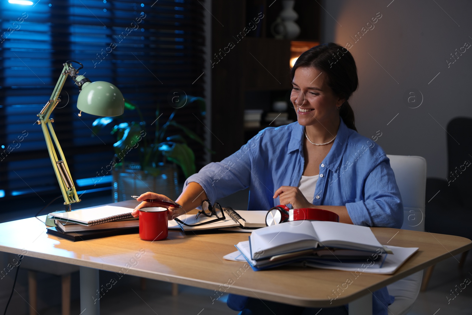 Photo of Happy student preparing for exam at wooden desk indoors