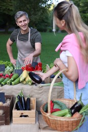 Photo of Woman choosing fresh vegetables from stall at farmer's market