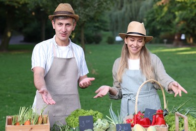 Photo of Happy farmers near stall with different fresh vegetables at market