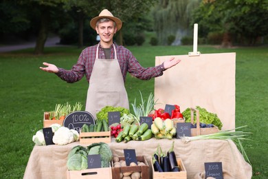 Photo of Happy farmer near stall with different fresh vegetables at market