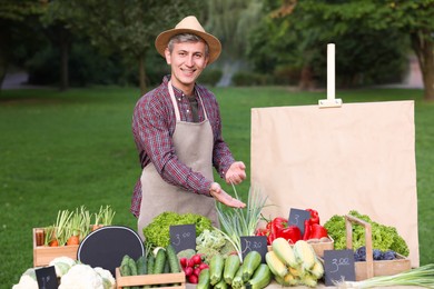 Photo of Happy farmer near stall with different fresh vegetables at market
