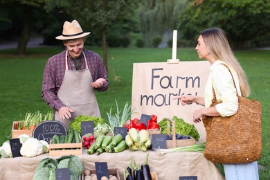 Photo of Woman choosing fresh vegetables from stall at farmer's market