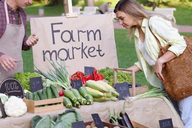 Photo of Woman choosing fresh vegetables from stall at farmer's market