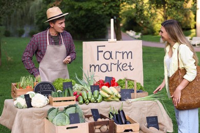 Photo of Woman choosing fresh vegetables from stall at farmer's market
