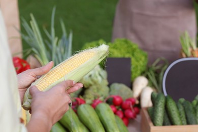 Photo of Woman choosing fresh vegetables from stall at farmer's market, closeup