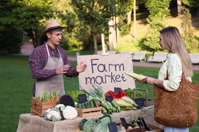 Photo of Woman choosing fresh vegetables from stall at farmer's market
