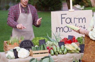 Photo of Woman choosing fresh vegetables from stall at farmer's market, closeup