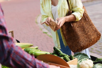 Photo of Woman choosing fresh vegetables from stall at farmer's market, closeup