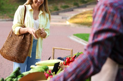 Photo of Woman choosing fresh vegetables from stall at farmer's market, closeup