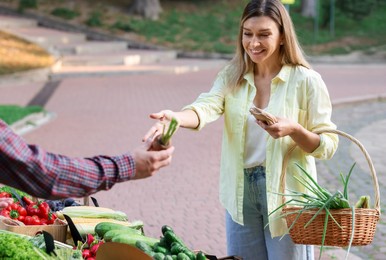 Photo of Woman choosing fresh vegetables from stall at farmer's market