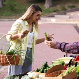 Photo of Woman choosing fresh vegetables from stall at farmer's market