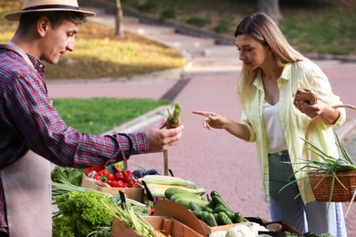 Photo of Woman choosing fresh vegetables from stall at farmer's market