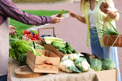 Photo of Woman choosing fresh vegetables from stall at farmer's market, closeup