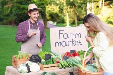 Photo of Woman choosing fresh vegetables from stall at farmer's market