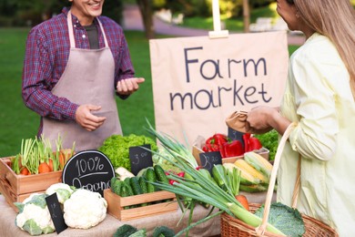 Photo of Woman choosing fresh vegetables from stall at farmer's market, closeup