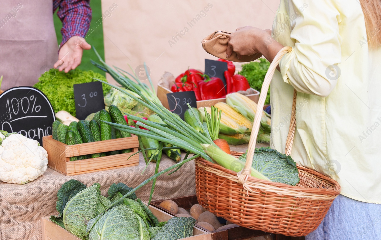 Photo of Woman choosing fresh vegetables from stall at farmer's market, closeup