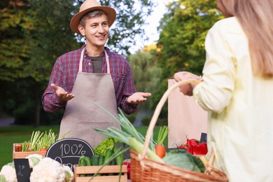 Photo of Woman choosing fresh vegetables from stall at farmer's market, closeup