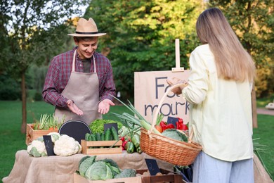 Photo of Woman choosing fresh vegetables from stall at farmer's market