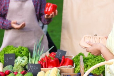 Photo of Woman choosing fresh vegetables from stall at farmer's market, closeup