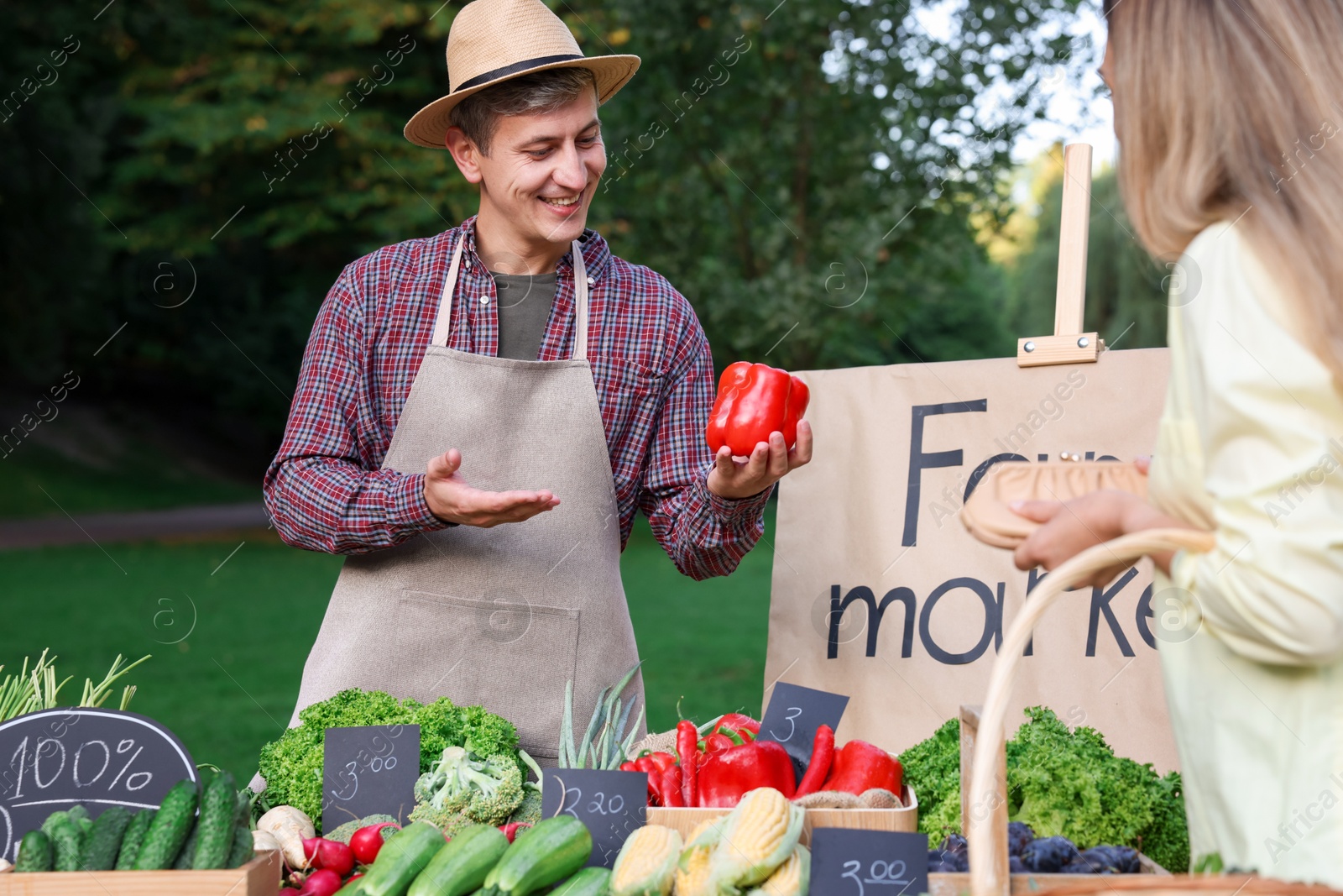 Photo of Woman choosing fresh vegetables from stall at farmer's market