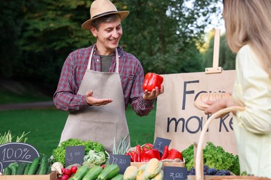 Photo of Woman choosing fresh vegetables from stall at farmer's market