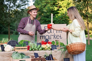 Photo of Woman choosing fresh vegetables from stall at farmer's market