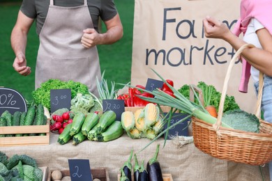 Photo of Woman choosing fresh vegetables from stall at farmer's market, closeup