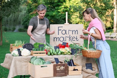 Photo of Woman choosing fresh vegetables from stall at farmer's market