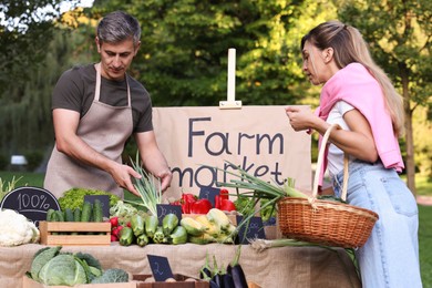 Photo of Woman choosing fresh vegetables from stall at farmer's market