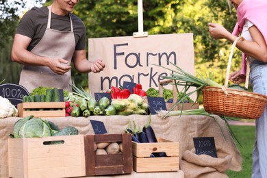 Photo of Woman choosing fresh vegetables from stall at farmer's market, closeup