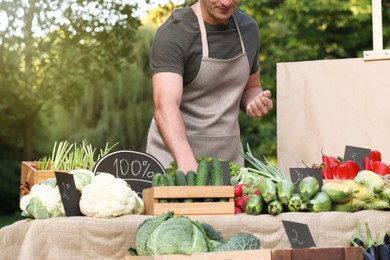 Photo of Farmer near stall with different fresh vegetables at market, closeup