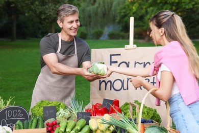 Photo of Woman choosing fresh vegetables from stall at farmer's market